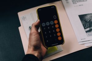 Man holding a smartphone showing a calculator app on the screen.